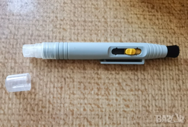 Уред с четка и пръскаща част за почистване на лещи и обективи